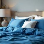 A beautifully made bed with deep blue sapphire sheets, white pillows, and elegant bedroom décor in natural lighting