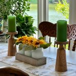 A modern dining room centerpiece featuring a large glass bowl filled with floating candles, surrounded by smaller glass votive holders and decorative glass spheres