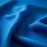 Close-up texture shot showing the weave pattern and luxurious sheen of high-quality sapphire blue sheets