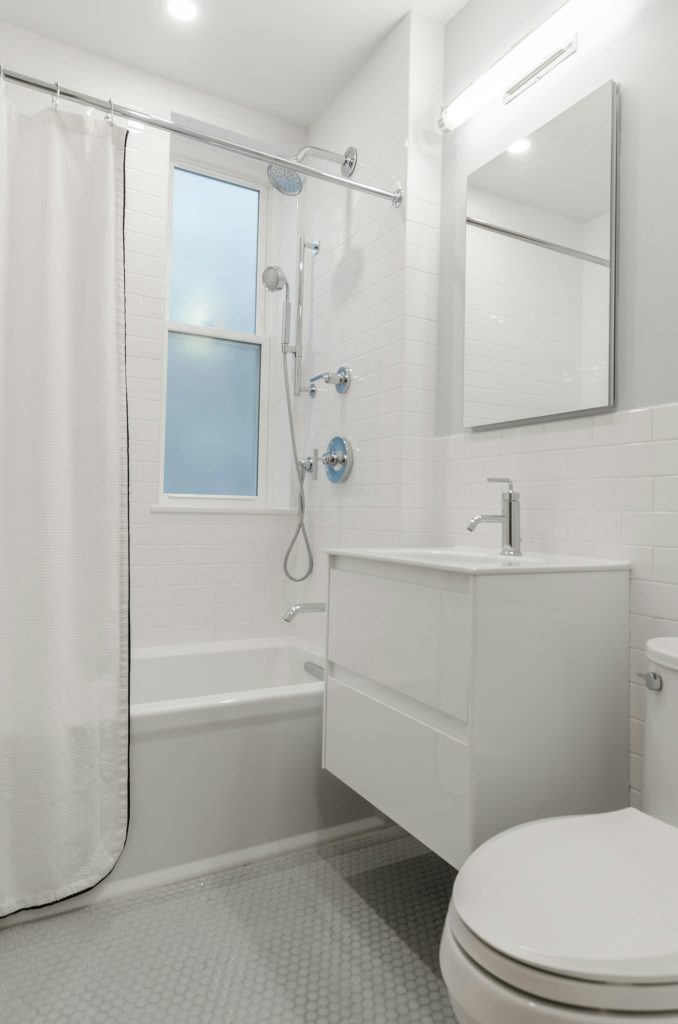 A before-and-after split image showing a messy, outdated bathroom on the left and a clean, renovated bathroom with white tiles and a modern shower on the right