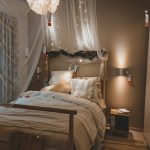 A cozy bedroom with soft bedding, a wooden bed frame, warm lighting, and minimalist décor on the nightstand