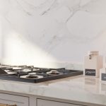 A modern kitchen with clean white cabinets, a marble countertop, and organized shelving with neatly placed jars and utensils