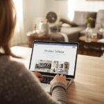 A person on a laptop or tablet visiting myinteriorpalace.com  the DrHomey interior design guide open on the screen. Warm home office setting.