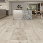 A beautiful modern kitchen with large-format porcelain tile flooring, showing clean grout lines and a seamless transition from the kitchen to a dining area.